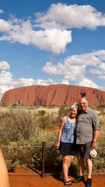 Tour guide taking a couples photo with Ayers Rock in the background